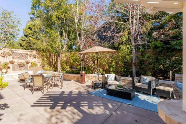 a view of a patio with table and chairs under an umbrella with large trees