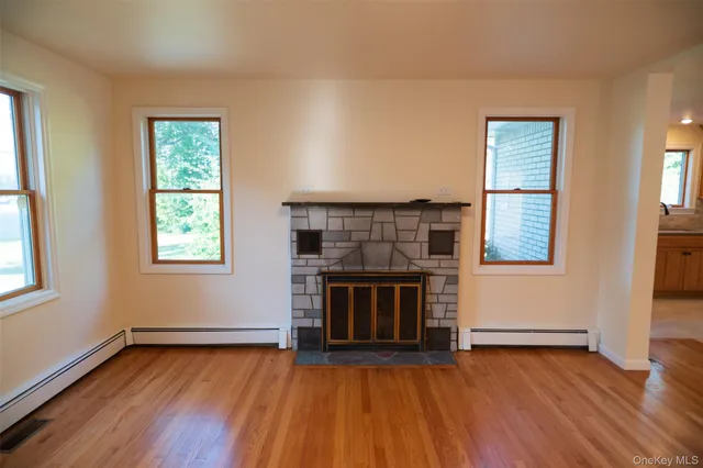 an empty room with wooden floor fireplace and windows