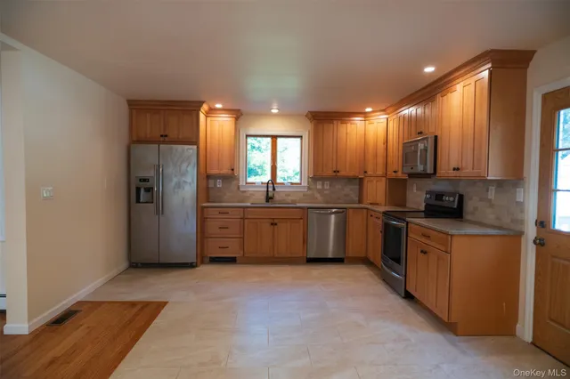 a large kitchen with kitchen island a sink stainless steel appliances and cabinets