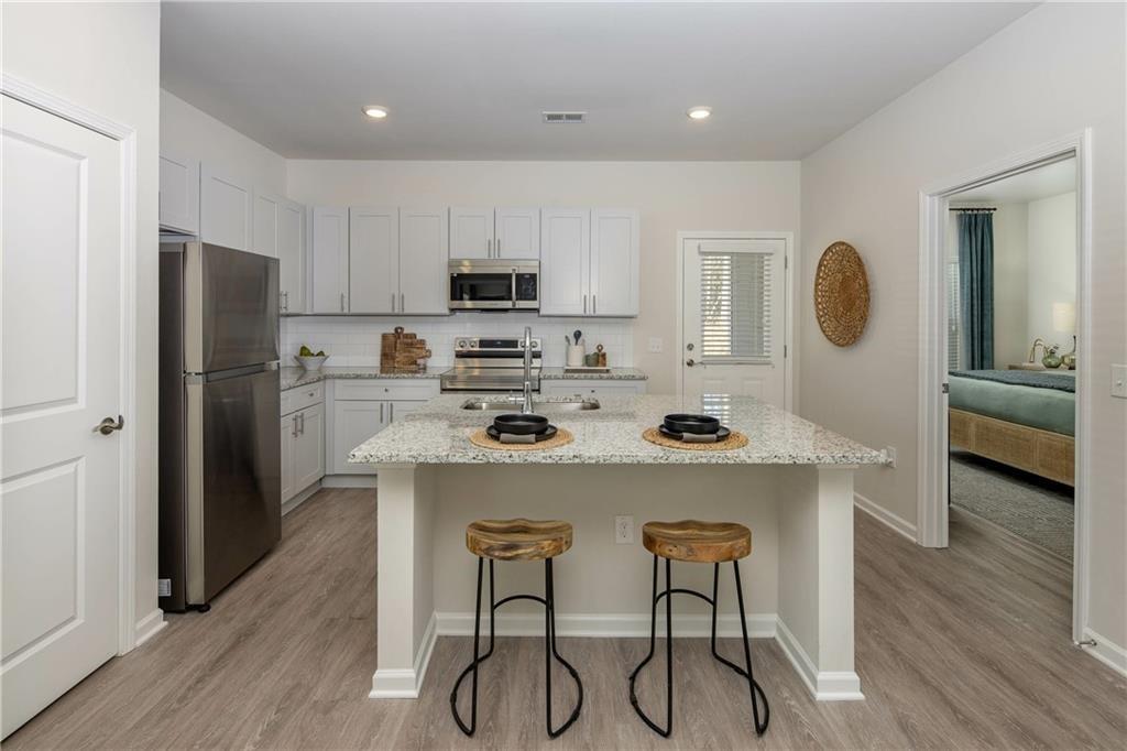 101 Walker Ridge Lane, Unit GINGER Cartersville, GA 30120 - Photo 19 of 40 a kitchen with stainless steel appliances a stove a refrigerator and a dining table with wooden floor