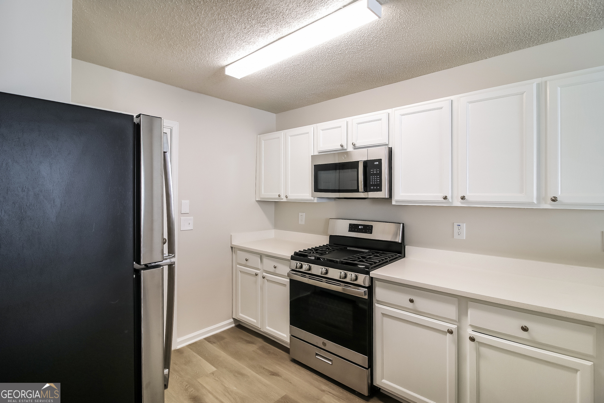 165 Colser Drive Covington, GA 30016 - Photo 7 of 17 a kitchen with stainless steel appliances white cabinets and a stove top oven