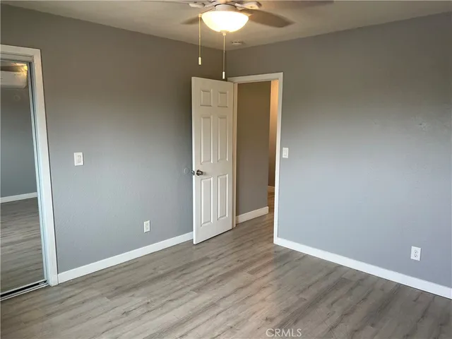 an empty room with wooden floor and chandelier fan