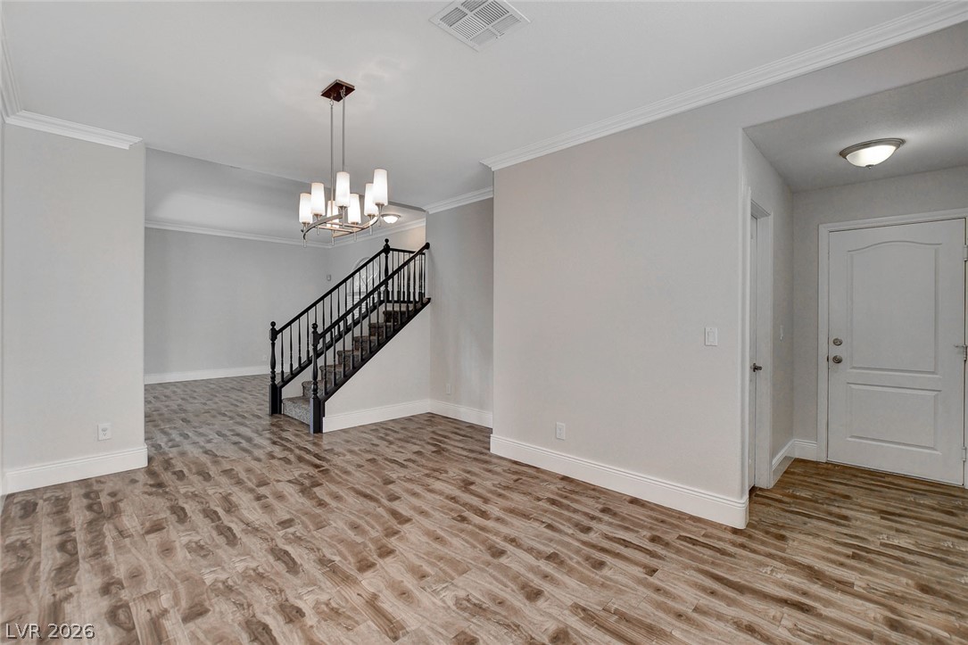 191 Verde Ridge Court Henderson, NV 89012 - Photo 6 of 36 Spare room with wood finished floors, baseboards, a chandelier, ornamental molding, and stairs