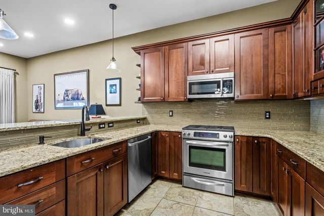 a kitchen with stainless steel appliances granite countertop wooden cabinets and a sink