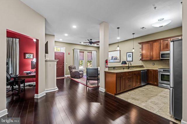 a kitchen with stainless steel appliances kitchen island granite countertop a refrigerator a stove top oven and sink with wooden floor