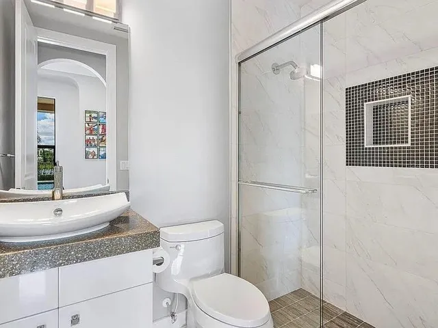 a bathroom with a granite countertop sink toilet and shower