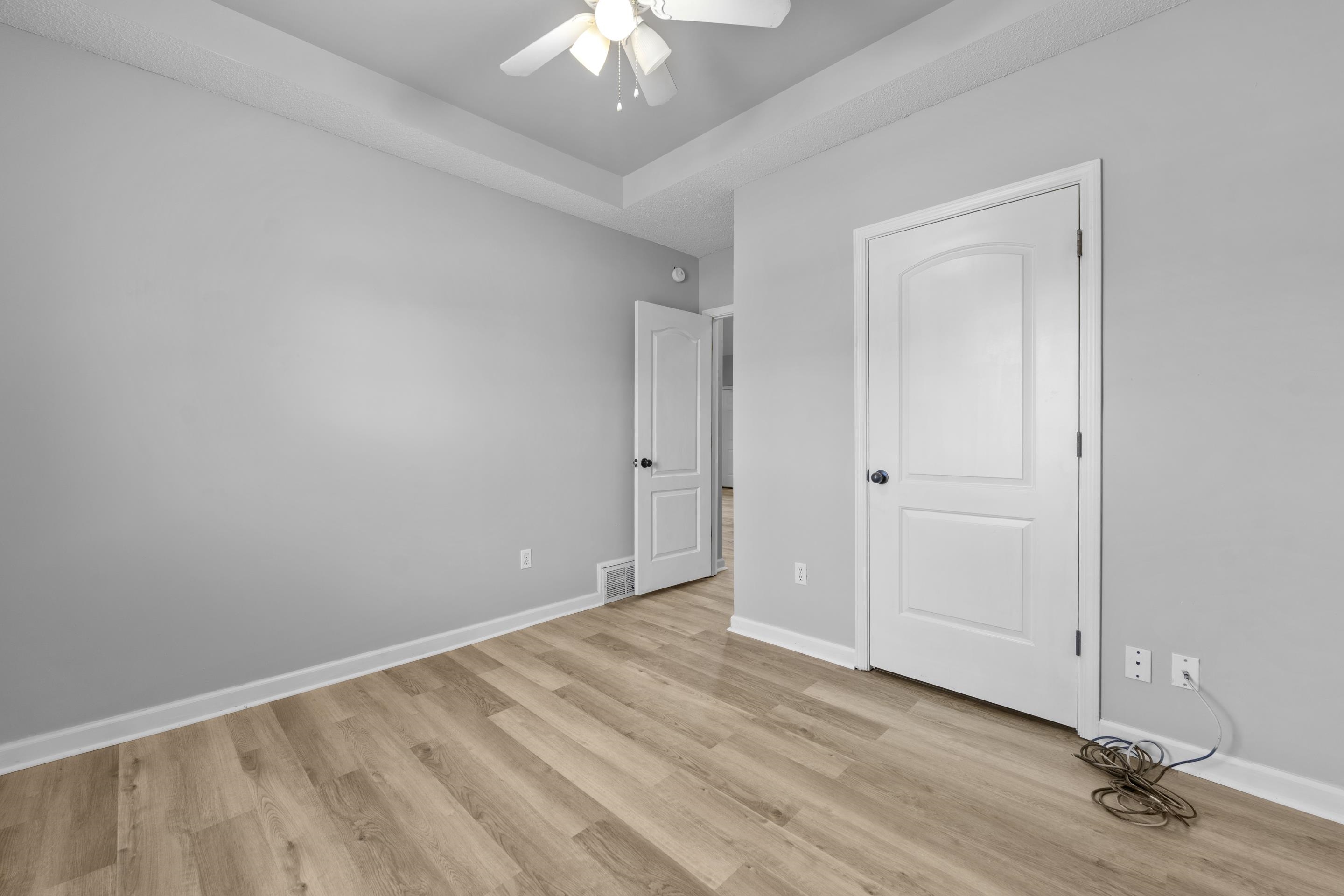 50 Abbey Road Oakland, TN 38060 - Photo 15 of 26 Bedroom featuring light gray walls, wood-finish flooring, a tray ceiling, and a ceiling fan