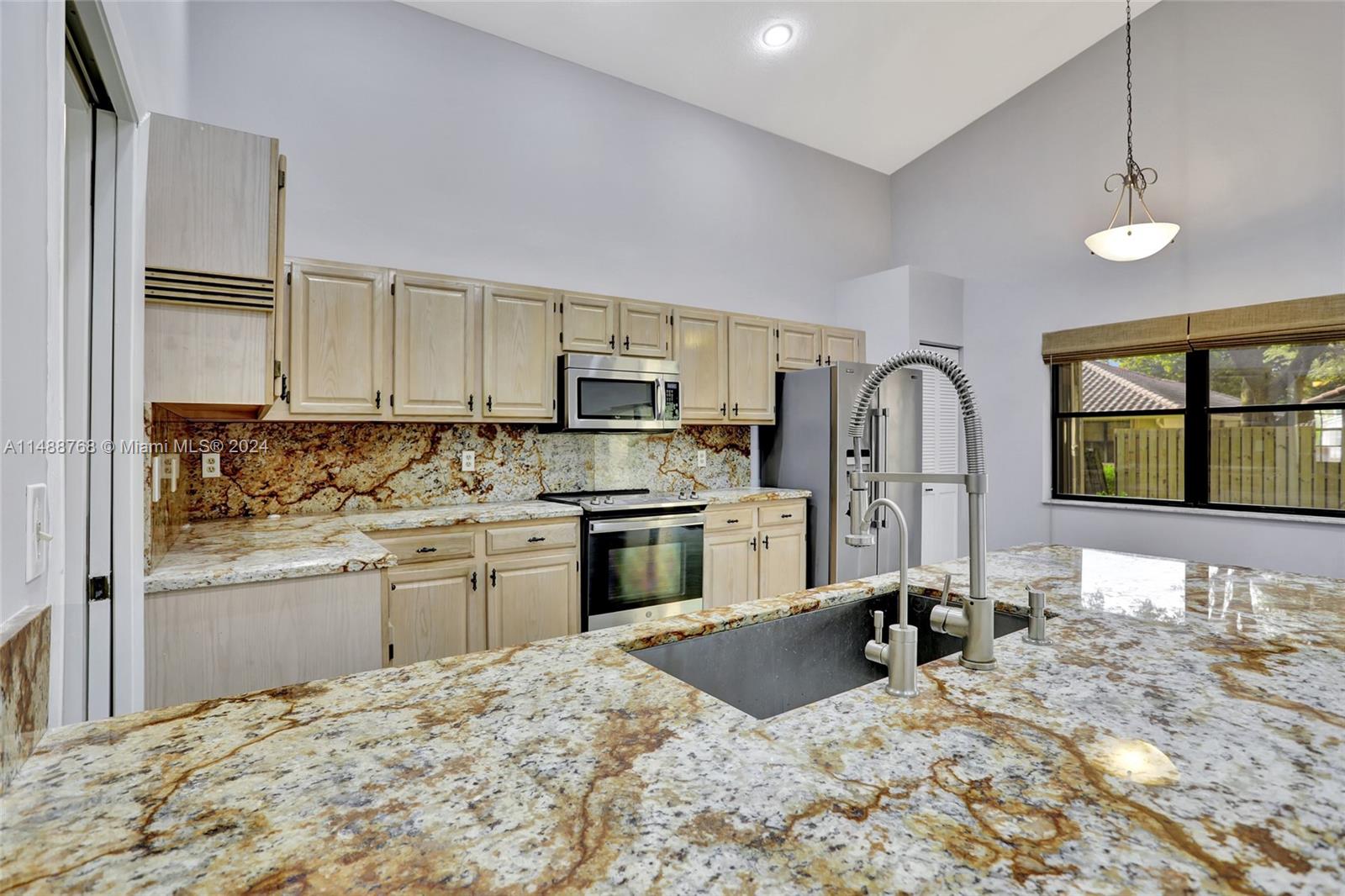 9641 Ridgeside Court Davie, FL 33328 - Photo 22 of 47 a kitchen with stainless steel appliances kitchen island granite countertop a stove a sink and a refrigerator