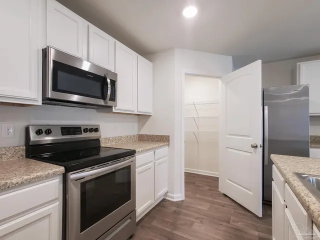 a kitchen with stainless steel appliances granite countertop white cabinets and a stove a oven with white countertops