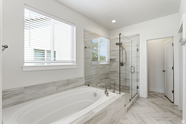 108 West Monte Rosa Lane Midway, UT 84049 - Photo 19 of 48 Spacious bathroom featuring a built-in soaking tub, a frameless glass shower enclosure with a built-in niche, floor-to-ceiling tile in the shower, large format tile surrounding the tub, and herringbone pattern tile flooring