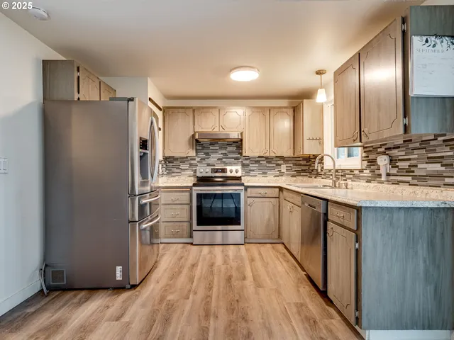 a kitchen with granite countertop stainless steel appliances and wooden floor
