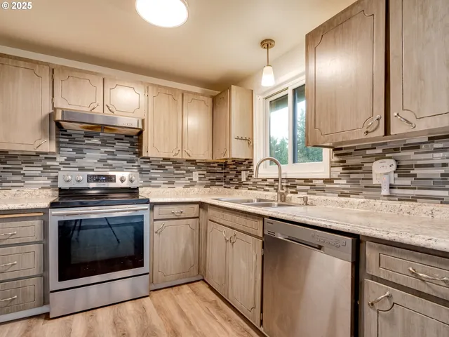 a kitchen with granite countertop a sink stainless steel appliances and cabinets