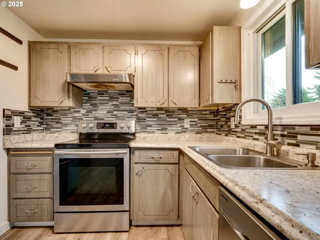 a kitchen with stainless steel appliances granite countertop a sink cabinets and wooden floor