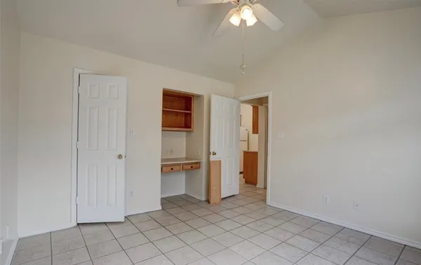 an empty room with chandelier fan and window
