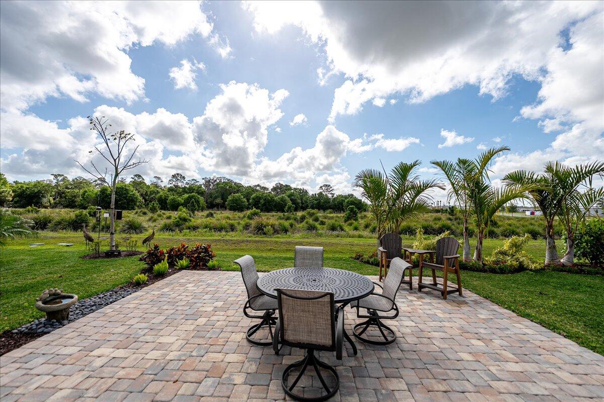 9941 Southwest Legacy Drive Stuart, FL 34997 - Photo 25 of 33 a view of a patio with table and chairs potted plants and lake view