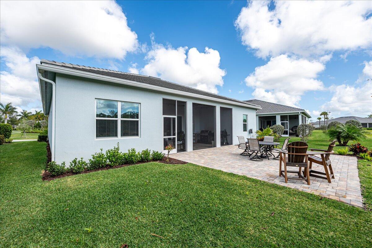 9941 Southwest Legacy Drive Stuart, FL 34997 - Photo 26 of 33 a view of a backyard with table and chairs potted plants and a palm tree