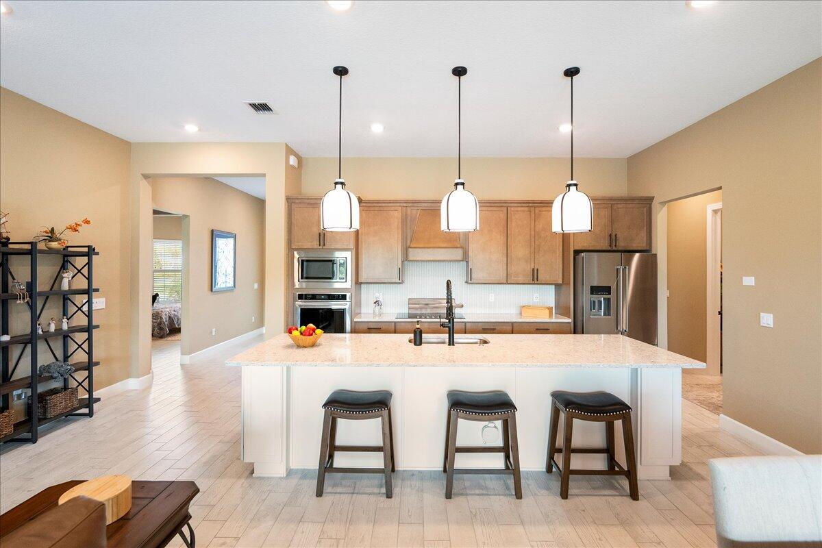 9941 Southwest Legacy Drive Stuart, FL 34997 - Photo 3 of 33 a dining hall with stainless steel appliances kitchen island granite countertop a dining table chairs and a view of living room