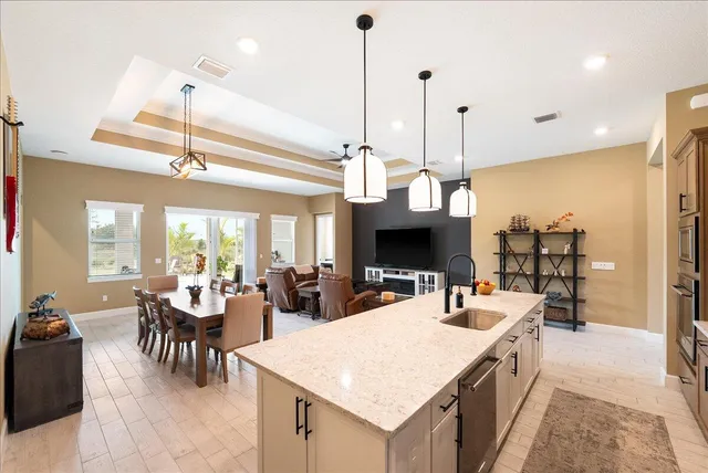 a dining room with stainless steel appliances kitchen island granite countertop a dining table chairs and a refrigerator