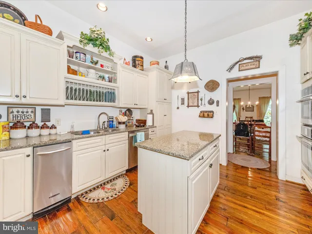 a kitchen with stainless steel appliances granite countertop a refrigerator a oven and a sink with wooden floor