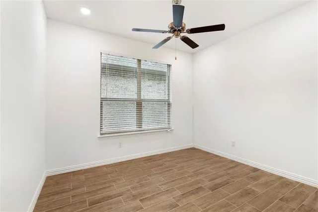 an empty room with a window and a ceiling fan