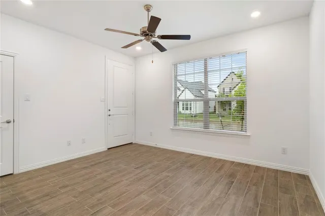 an empty room with wooden floor fan and windows