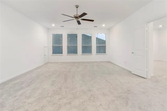 an empty room with ceiling fan and windows