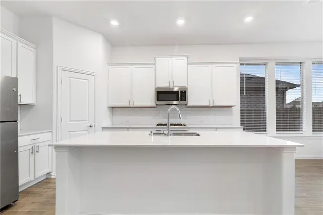a view of a kitchen with kitchen island a sink stainless steel appliances and cabinets