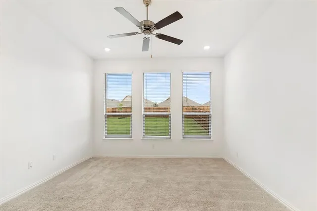 an empty room with windows and ceiling fan