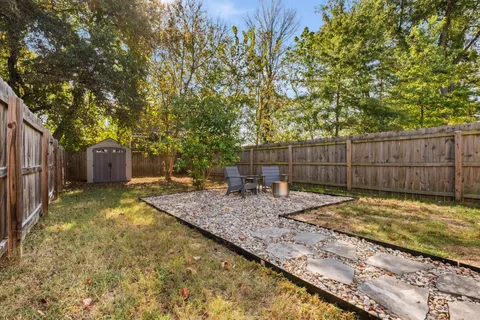 a view of a backyard with wooden fence and a large tree
