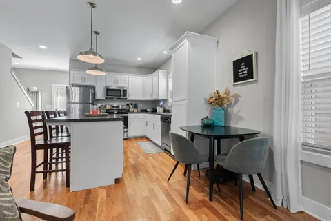 a kitchen with stainless steel appliances granite countertop a dining table chairs microwave and sink