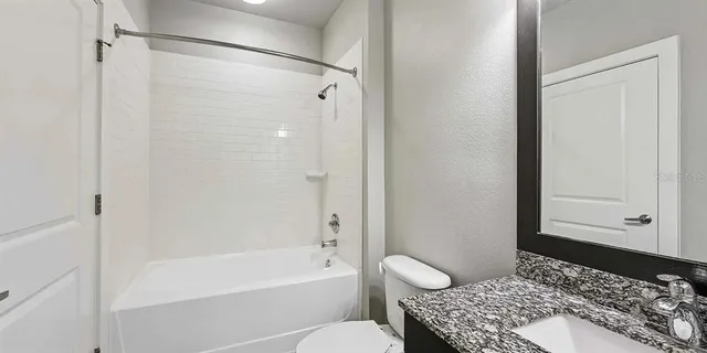 a bathroom with a tub shower sink and a toilet