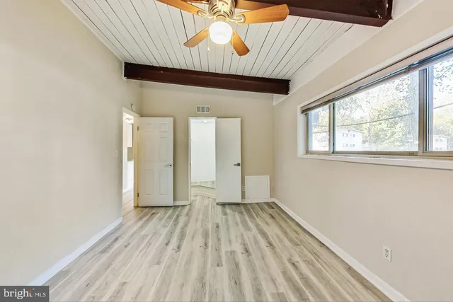 a view of hallway with window and wooden floor