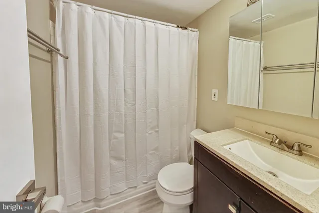 a bathroom with a granite countertop sink toilet and a mirror