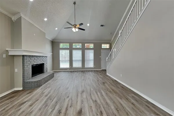 a view of an empty room with wooden floor fireplace and a window