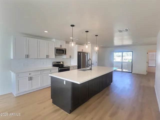 a large white kitchen with wooden floors and stainless steel appliances