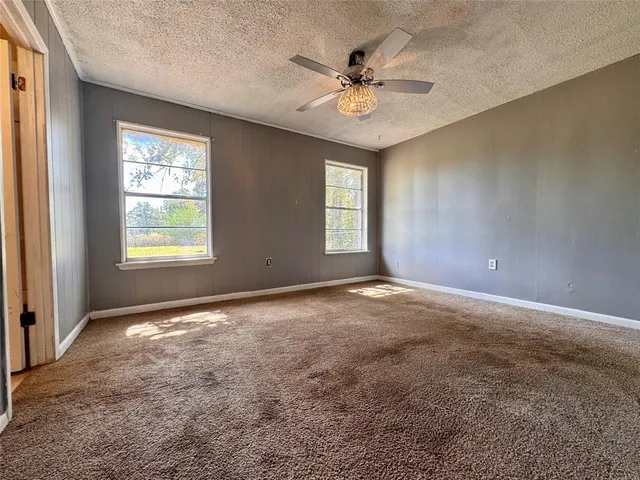 an empty room with windows and fan