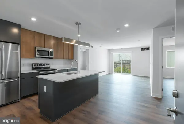 a kitchen with stainless steel appliances granite countertop a stove a refrigerator a sink a microwave oven with cabinets and wooden floor