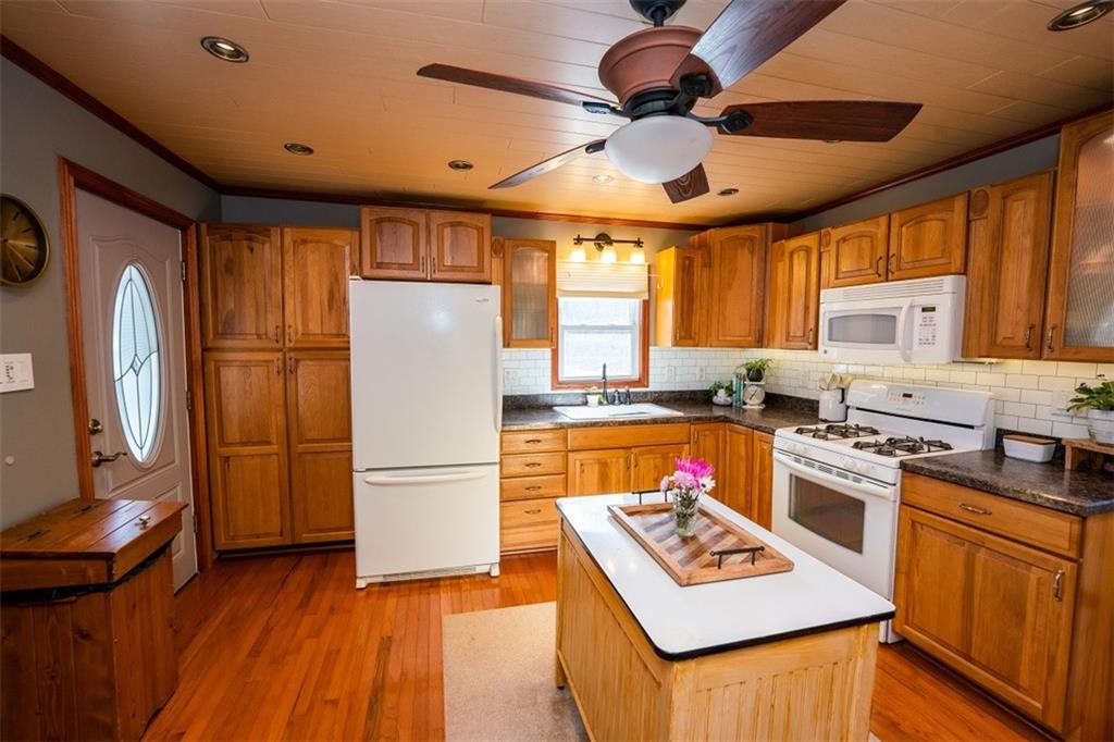 232 Lighthouse Road Commodore, PA 15729 - Photo 4 of 17 a kitchen with stainless steel appliances granite countertop a refrigerator a stove top oven a sink dishwasher and white cabinets with wooden floor