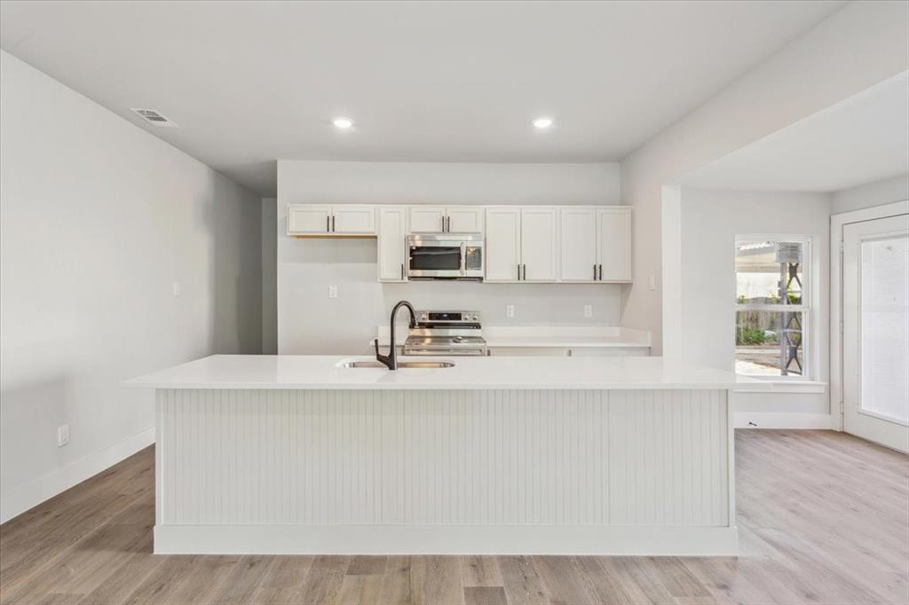 900 North 22nd Street Waco, TX 76707 - Photo 6 of 37 a kitchen with stainless steel appliances granite countertop a sink a stove a refrigerator with white cabinets and wooden floor