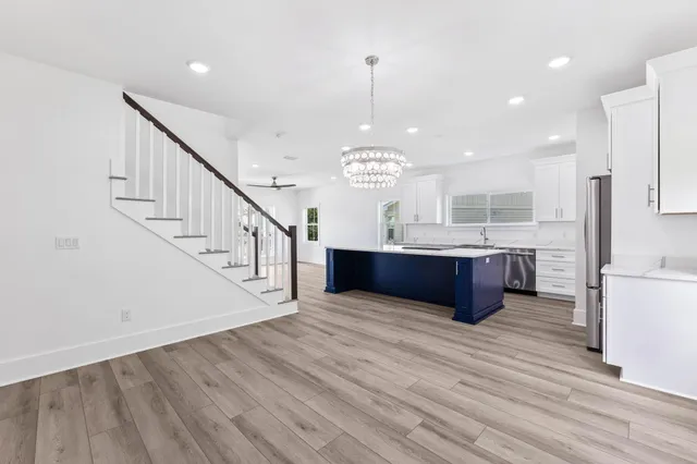 an empty room with wooden floor chandelier fan and windows