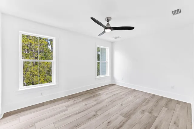 a view of empty room with wooden floor and fan