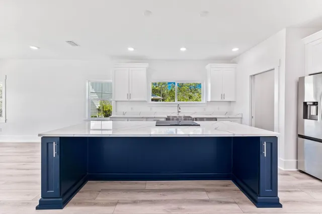 a kitchen with stainless steel appliances granite countertop a sink dishwasher a stove and a refrigerator with wooden floor