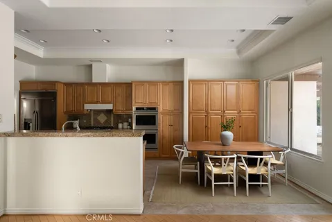 a kitchen with stainless steel appliances kitchen island granite countertop a table and chairs in it