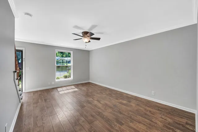 a view of an empty room with a window and wooden floor