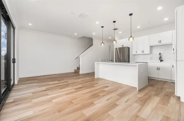 a view of a kitchen with kitchen island a sink stainless steel appliances and a chandelier