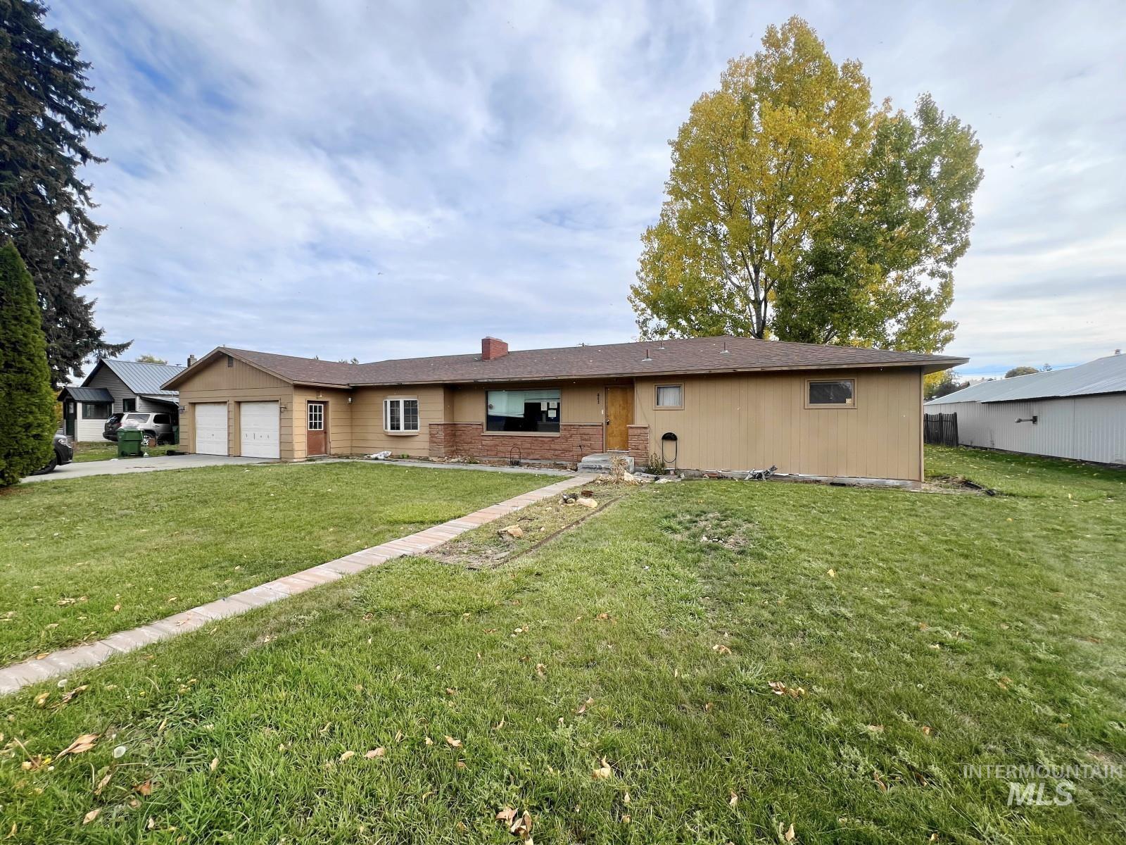 View of front of home with a front yard, a garage, brick siding, and concrete driveway