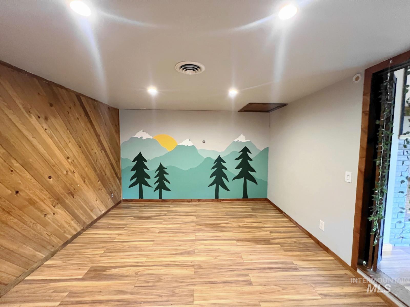 603 Maple Street Nezperce, ID 83543 - Photo 5 of 26 Empty room with light wood-style flooring and wood walls