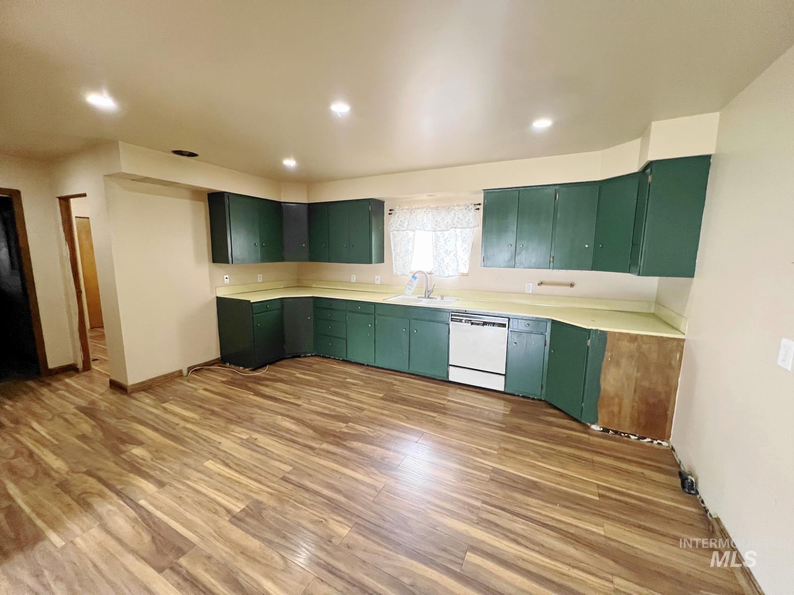 603 Maple Street Nezperce, ID 83543 - Photo 9 of 26 Kitchen with green cabinets, wood finished floors, light countertops, white dishwasher, and recessed lighting