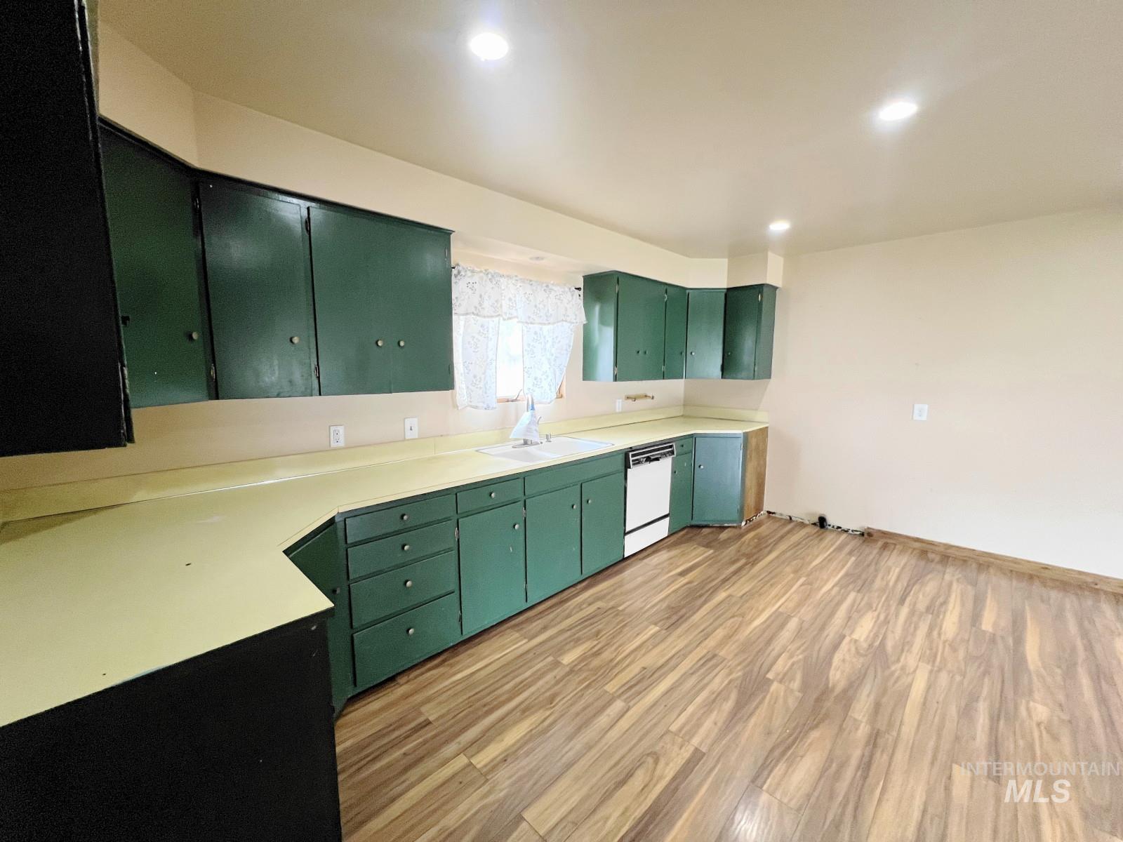 603 Maple Street Nezperce, ID 83543 - Photo 10 of 26 Kitchen with green cabinets, light countertops, light wood finished floors, and white dishwasher