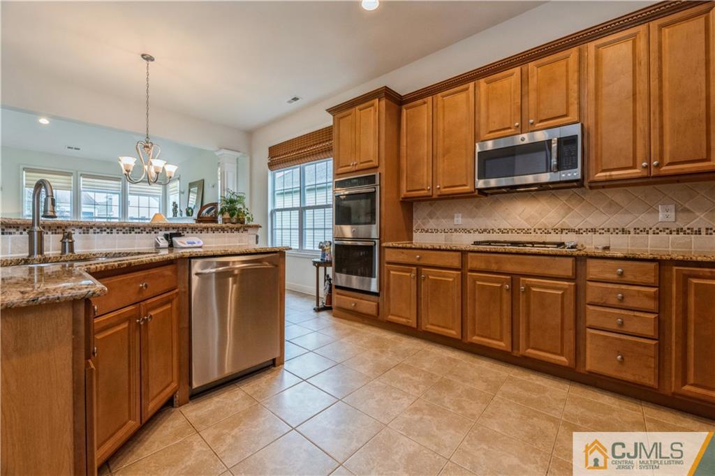 18 Mandrake Road Monroe Township, NJ 08831 - Photo 11 of 44 a kitchen with stainless steel appliances granite countertop a stove top oven a sink dishwasher and cabinets with wooden floor